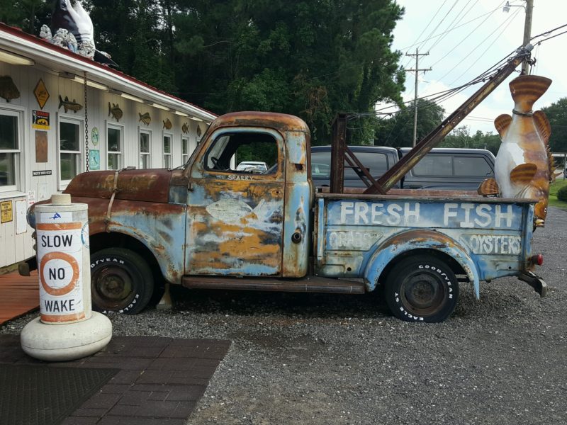 An old truck parked on the side of a building