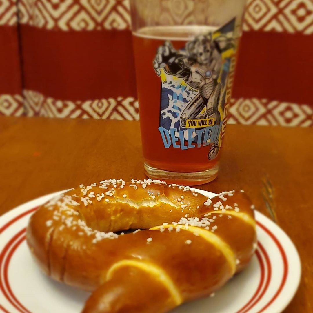 a glass of beer with a soft pretzel