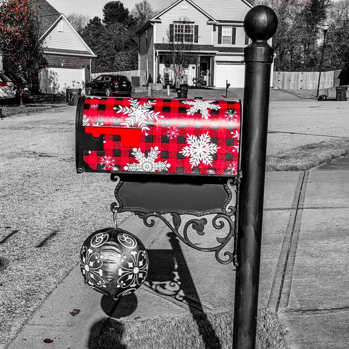 Black and white photograph with a color pop red mailbox.